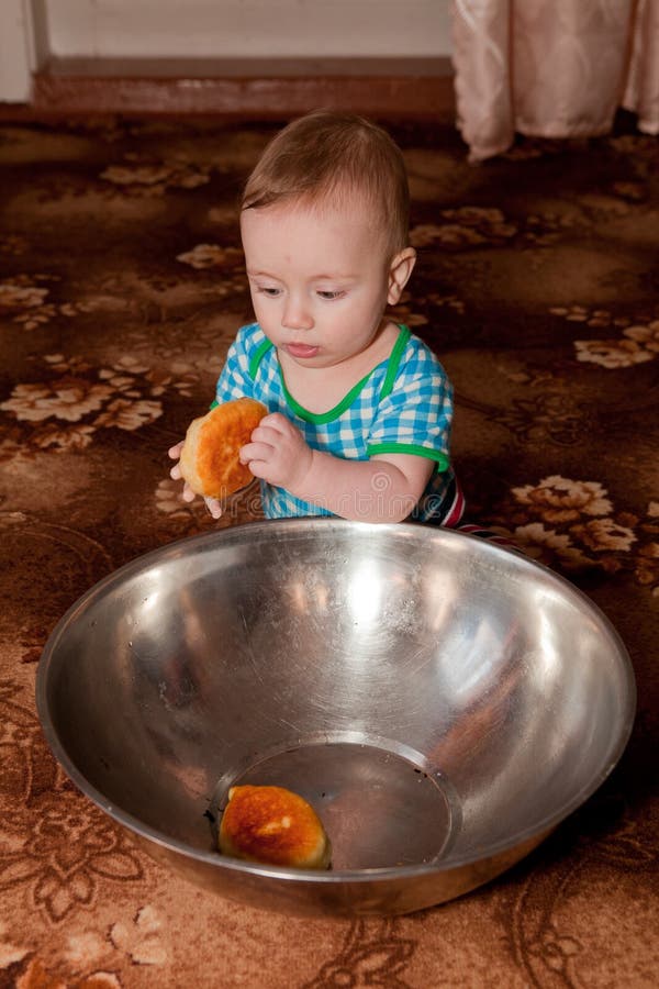 Un ragazzo piacevole che mangia una ciambella di grande ciotola immagine stock libera da diritti Un ragazzo piacevole che mangia una ciambella di grande ciotola immagine stock libera da diritti