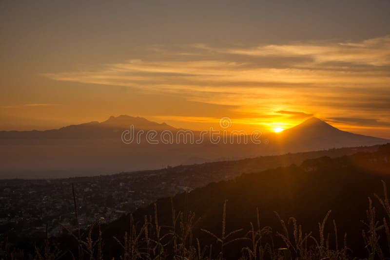 Sun peeking behind the volcanoes