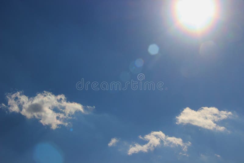 Un rayon du soleil d'or contre un ciel bleu lumineux avec de petits nuages photos stock Un rayon du soleil d'or contre un ciel bleu lumineux avec de petits nuages photos stock
