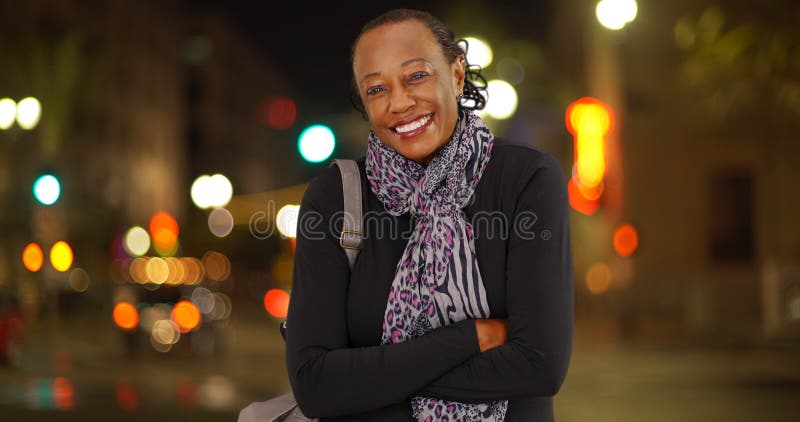 Un retrato de una más vieja mujer afroamericana que ríe en el tiempo frío en una esquina de calle muy transitada imagen de archivo libre de regalías