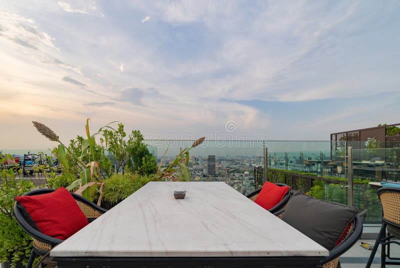 Un ristorante o una terrazza di bar con tavola sul tetto dell'hotel, un edificio ad alta ascesa con vista in città fotografia stock libera da diritti