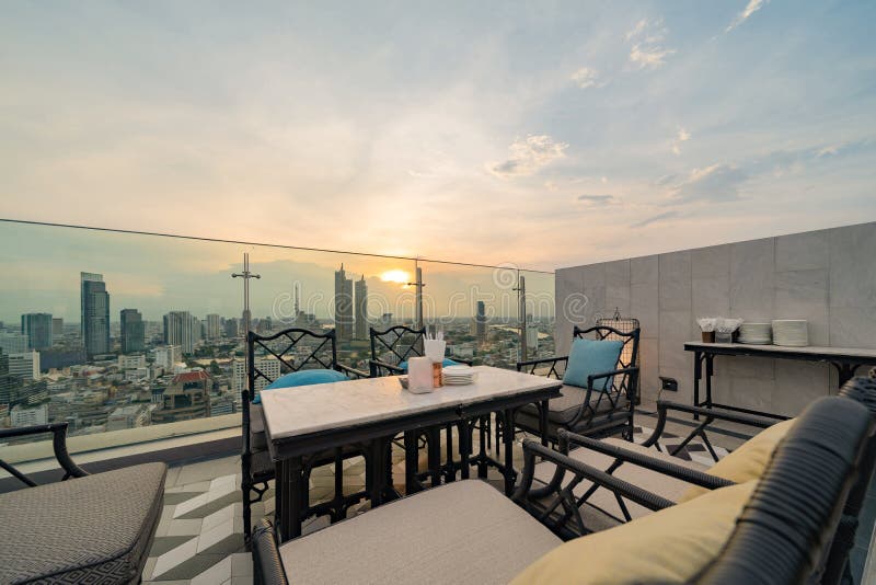 Un ristorante o una terrazza di bar con tavola sul tetto dell'hotel, un edificio ad alta ascesa con vista in città fotografia stock libera da diritti