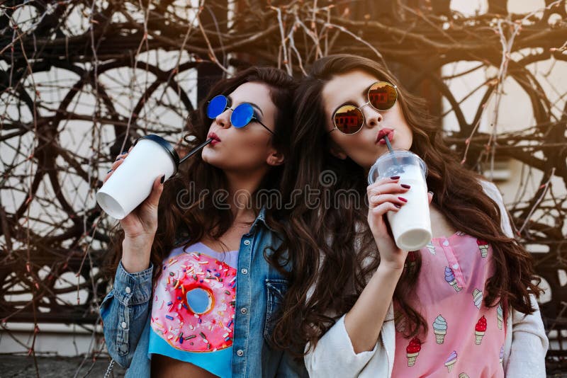 Un ritratto all'aperto di stile di vita di modo di due giovani belle donne, vestito in attrezzatura del denim, ha rispecchiato gl fotografie stock libere da diritti Un ritratto all'aperto di stile di vita di modo di due giovani belle donne, vestito in attrezzatura del denim, ha rispecchiato gl fotografie stock libere da diritti