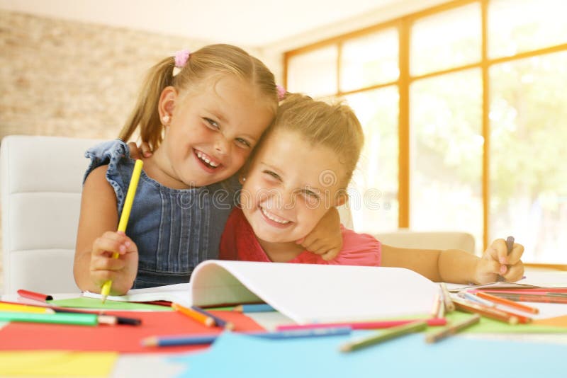 Un ritratto di un disegno e di un esame di due bambine della macchina fotografica fotografia stock Un ritratto di un disegno e di un esame di due bambine della macchina fotografica fotografia stock