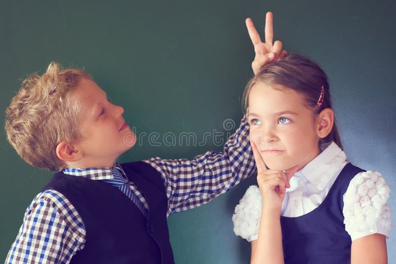 Un ritratto di due bei bambini ragazzo e ragazza dell'europeo in uniforme scolastico che sta accanto alla lavagna Il ragazzo most fotografia stock libera da diritti Un ritratto di due bei bambini ragazzo e ragazza dell'europeo in uniforme scolastico che sta accanto alla lavagna Il ragazzo most fotografia stock libera da diritti