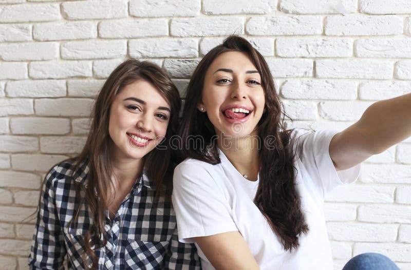 Un ritratto di due femmine millenarie, imbrogliante intorno davanti alla macchina fotografica mobile dello smartphone Brown ha os fotografia stock libera da diritti Un ritratto di due femmine millenarie, imbrogliante intorno davanti alla macchina fotografica mobile dello smartphone Brown ha os fotografia stock libera da diritti