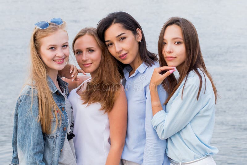 Un ritratto di quattro giovani amici femminili che camminano sulla riva di mare che esamina risata della macchina fotografica immagini stock Un ritratto di quattro giovani amici femminili che camminano sulla riva di mare che esamina risata della macchina fotografica immagini stock