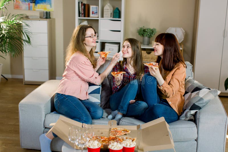Un ritratto di tre giovani amici femminili felici in abbigliamento casual che mangiano pizza sul sofà a casa Donne amicizia, mang immagini stock libere da diritti Un ritratto di tre giovani amici femminili felici in abbigliamento casual che mangiano pizza sul sofà a casa Donne amicizia, mang immagini stock libere da diritti