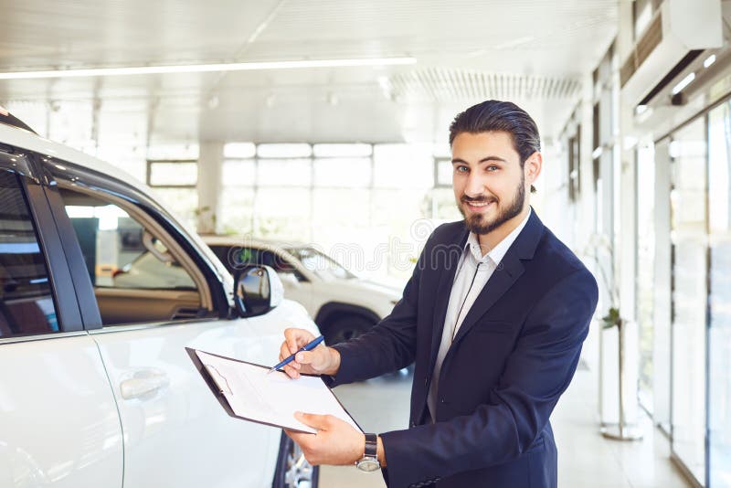 Un rivenditore di automobili detiene documenti sulla vendita di un'auto fotografia stock libera da diritti Un rivenditore di automobili detiene documenti sulla vendita di un'auto fotografia stock libera da diritti