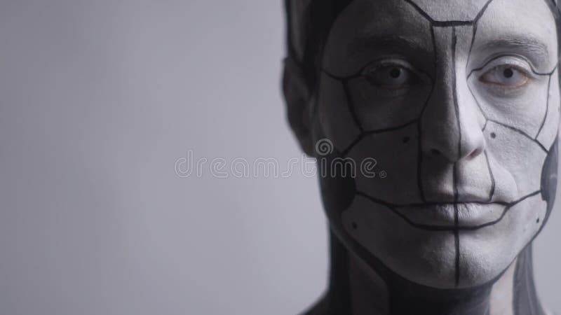 Un robot privo di emozioni sta su un fondo grigio e lampeggia video d archivio