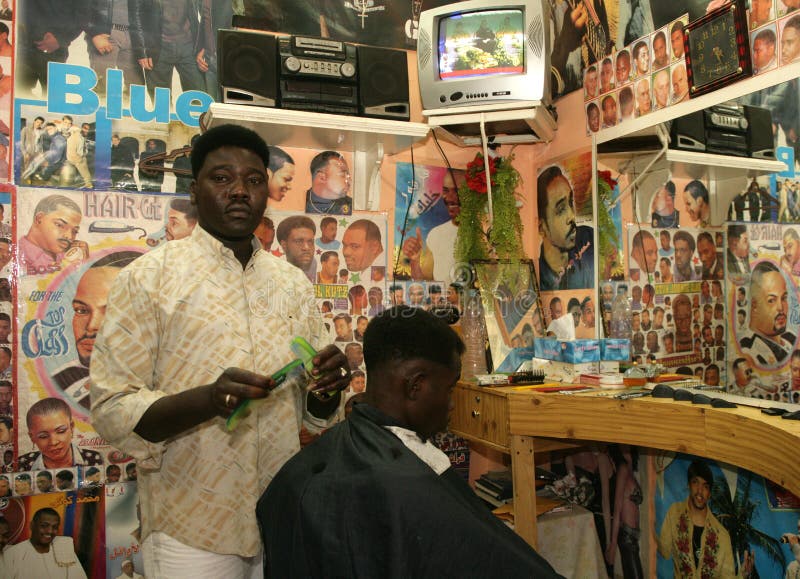 Un réfugié soudanais travaillant dans un salon de coiffure photographie stock libre de droits Un réfugié soudanais travaillant dans un salon de coiffure photographie stock libre de droits