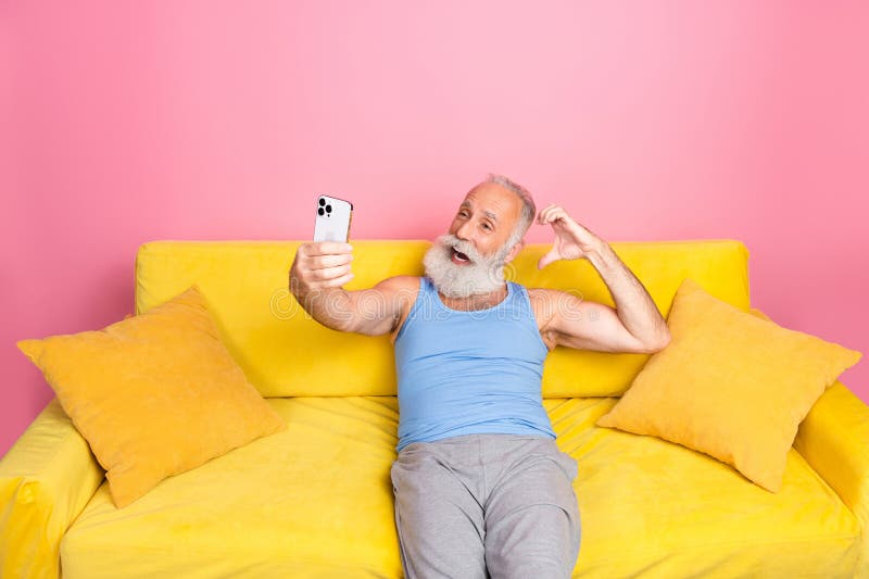 Un senior énergique prenant un selfie sur un canapé coloré à la maison images stock