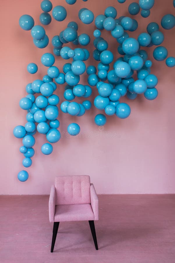 Un sillón de terciopelo rosa se alza contra una pared rosa con bolas azules Interior elegante imagen de archivo Un sillón de terciopelo rosa se alza contra una pared rosa con bolas azules Interior elegante imagen de archivo