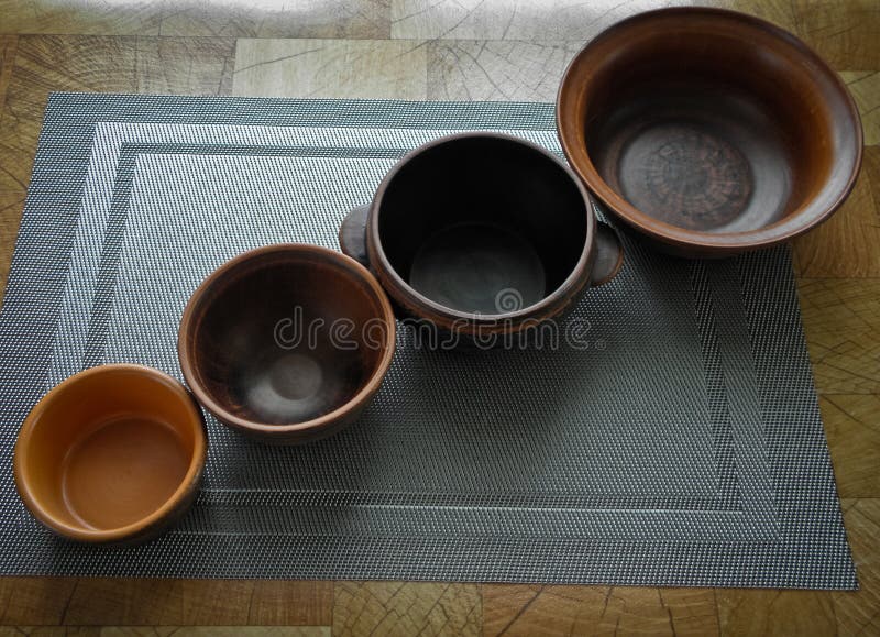 Un sistema de platos de la arcilla marrón en la tabla, en el mantel imagen de archivo Un sistema de platos de la arcilla marrón en la tabla, en el mantel imagen de archivo