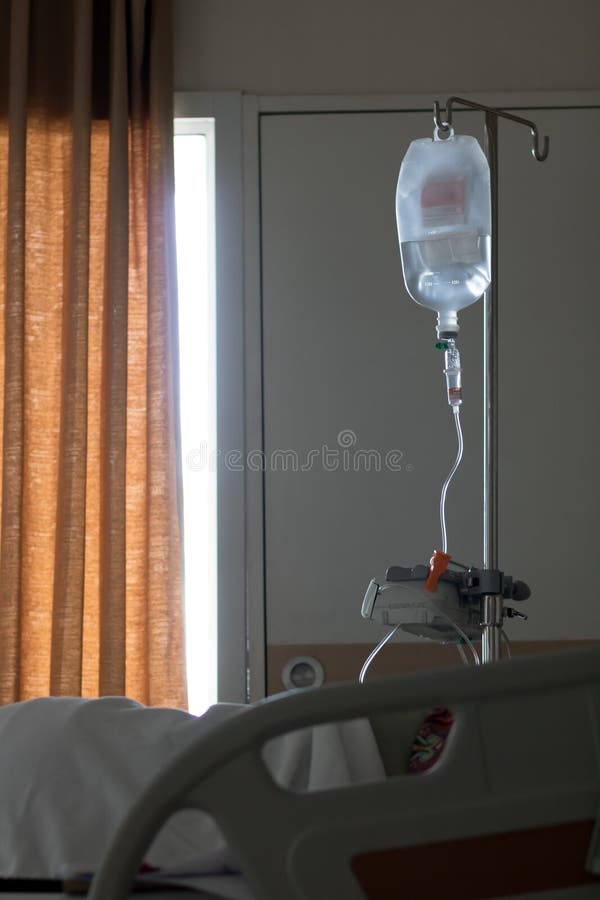 Un supporto con la borsa del gocciolamento accanto al letto all'ospedale immagine stock libera da diritti Un supporto con la borsa del gocciolamento accanto al letto all'ospedale immagine stock libera da diritti