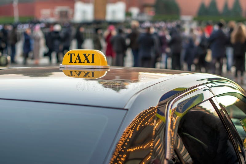 Un taxi parcheggiato sul marciapiede di grande via con i grandi ingorghi stradali, l'automobile riflette le luci della città di n immagine stock Un taxi parcheggiato sul marciapiede di grande via con i grandi ingorghi stradali, l'automobile riflette le luci della città di n immagine stock
