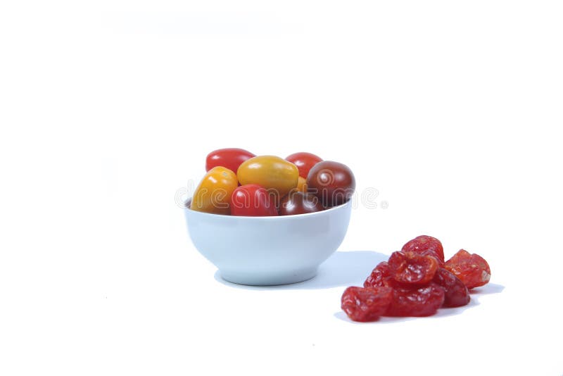 Un tazón de cerritomates y un montón de tomates secos aislados en fondo blanco plano. imagen horizontal fotos de archivo