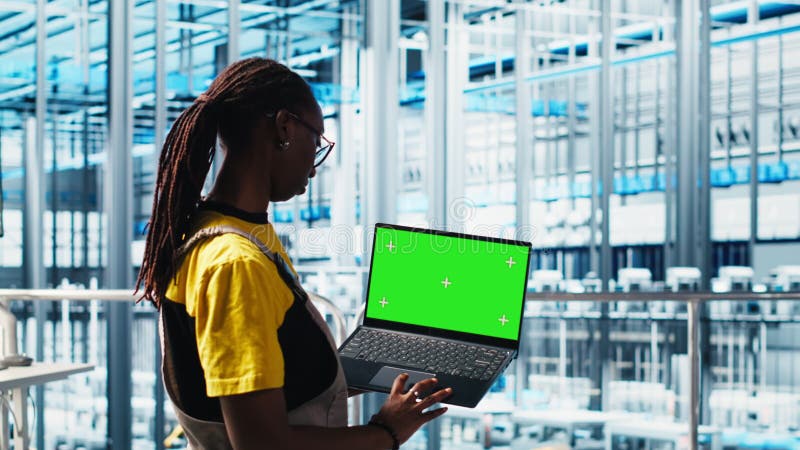 Un technicien d'usine intelligent gère les bras robotisés à l'aide d'un ordinateur portable mockup banque de vidéos