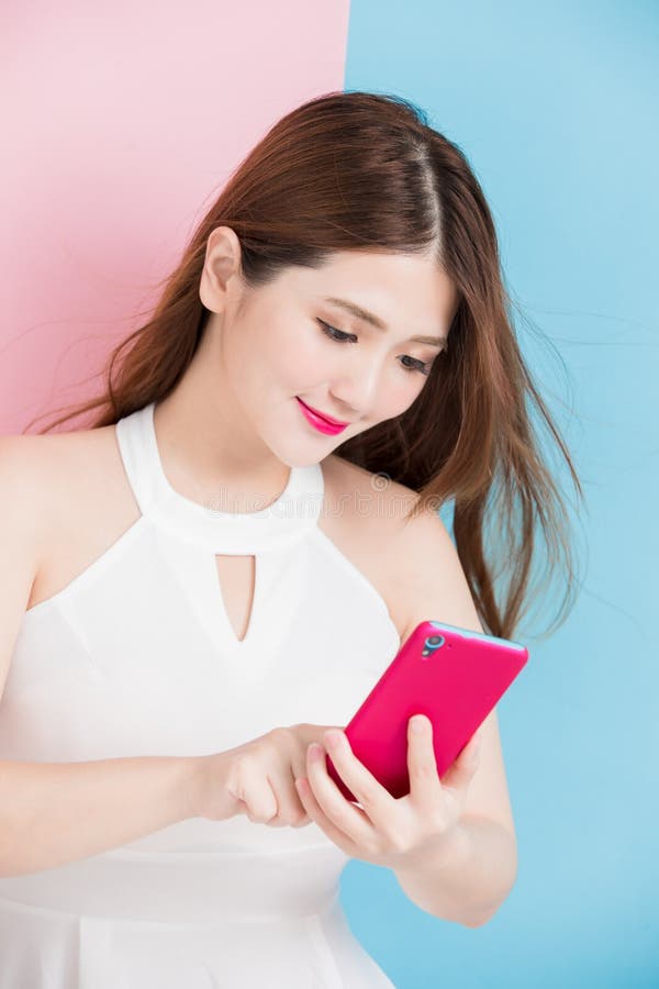 A pretty girl use smart phone isolated on pink and blue background. A pretty girl use smart phone isolated on pink and blue background
