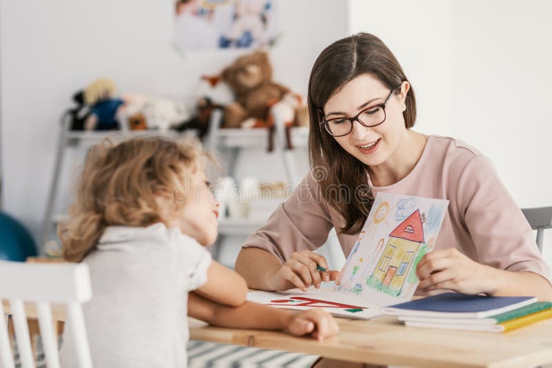 Un terapista professionista di istruzione del bambino che ha una riunione con un bambino in un centro di sostegno della famiglia immagine stock libera da diritti Un terapista professionista di istruzione del bambino che ha una riunione con un bambino in un centro di sostegno della famiglia immagine stock libera da diritti