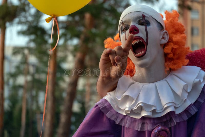 Un terrible clown aux dents acérées mord la main de quelqu'un Costume de carnaval ou d'halloween de vacances Cosplay à une fête d photos stock Un terrible clown aux dents acérées mord la main de quelqu'un Costume de carnaval ou d'halloween de vacances Cosplay à une fête d photos stock