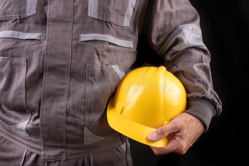 Un trabajador de producci?n en workwear con un casco protector en su mano Workwear especial para los empleados imágenes de archivo libres de regalías Un trabajador de producci?n en workwear con un casco protector en su mano Workwear especial para los empleados imágenes de archivo libres de regalías