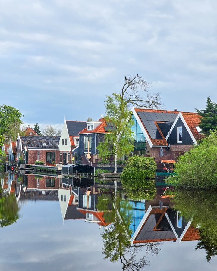 A tranquil body of water nestled among lush green trees and charming houses, creating a picturesque and idyllic scene of natural beauty old houses in Broek in Waterland in the Netherlands. A tranquil body of water nestled among lush green trees and charming houses, creating a picturesque and idyllic scene of natural beauty old houses in Broek in Waterland in the Netherlands