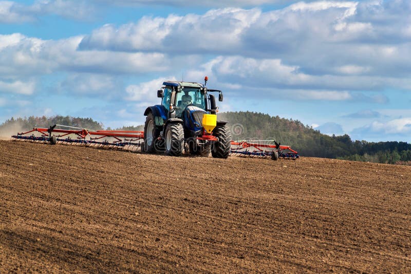 Un trattore azzurro semina grano Lavori agricoli in un'azienda agricola nella Repubblica ceca Trattore su un campo di frumento Ma