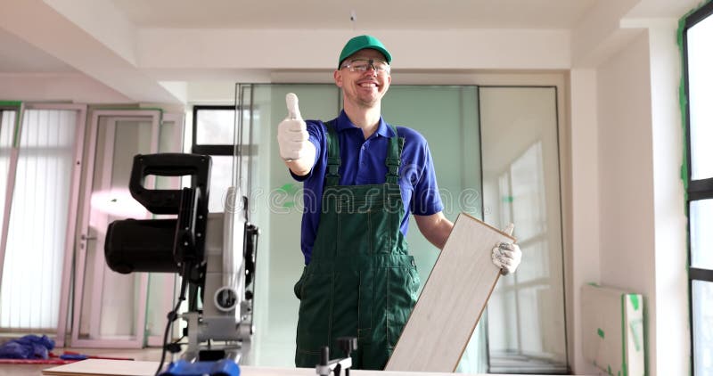 Un travailleur souriant montre un pouce debout près d'une machine à scier clips vidéos