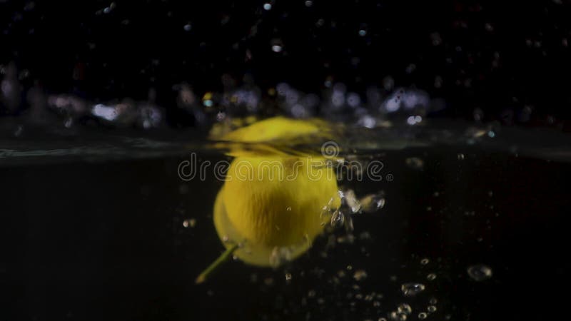 Un trozo de limón cae en el agua con un chorro Movimiento lento