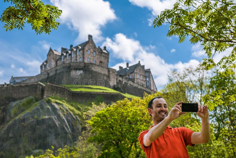 Un turista felice del giovane al castello di Edimburgo che prende selfie sulla m. fotografia stock libera da diritti Un turista felice del giovane al castello di Edimburgo che prende selfie sulla m. fotografia stock libera da diritti