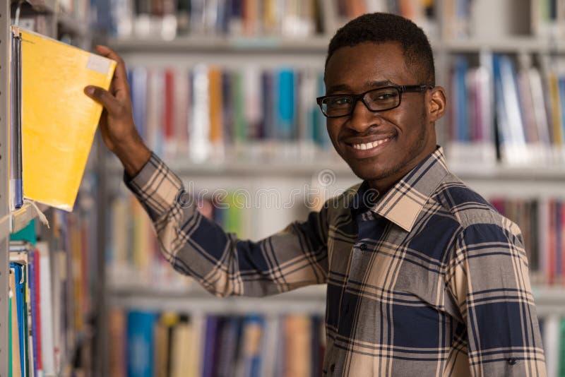 Un tânăr elev chipeș în bibliotecă. Un portret al unui student caucazian în bibliotecă, cu o adâncime superficială a câmpului