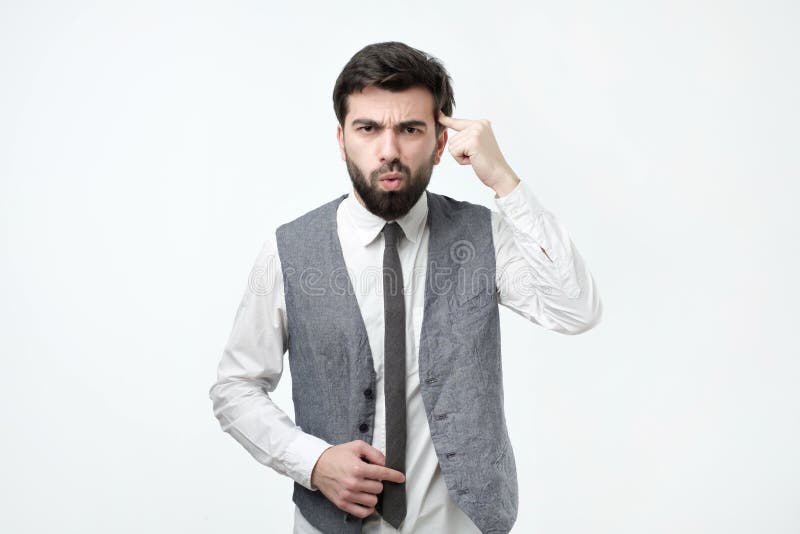 Un tânăr furios și furios gestând cu degetul la templu întrebând dacă ești nebun stock images