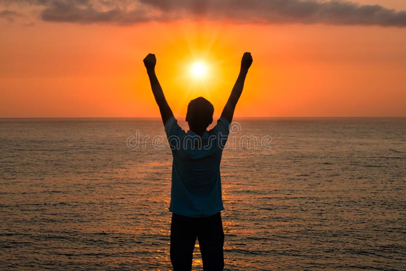 Image of a man praising or worshiping in front of the sea at sunrise with brilliant sun and glowing sun rays. Image of a man praising or worshiping in front of the sea at sunrise with brilliant sun and glowing sun rays.