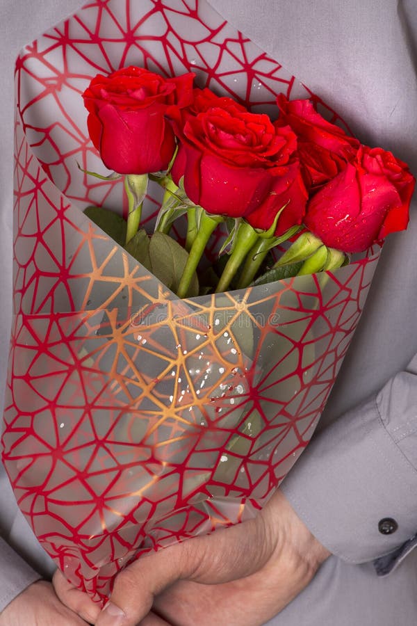 Un uomo che tiene un mazzo delle rose rosse immagine stock Un uomo che tiene un mazzo delle rose rosse immagine stock