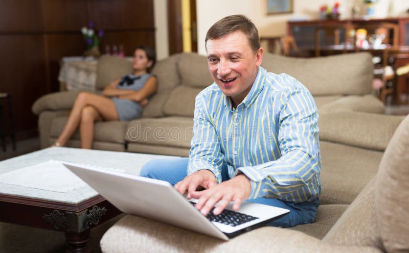 Un uomo con un computer portatile che ignora la moglie contrariata