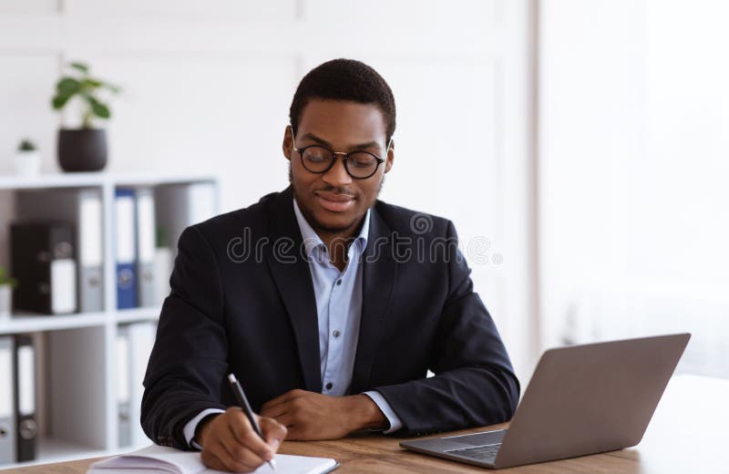 Un uomo d'affari nero entusiasta che sta pianificando la sua giornata in ufficio fotografie stock libere da diritti