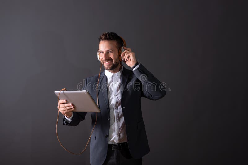 Un uomo d'affari sorridente che per mezzo di una compressa ed ascoltando la musica fotografie stock Un uomo d'affari sorridente che per mezzo di una compressa ed ascoltando la musica fotografie stock