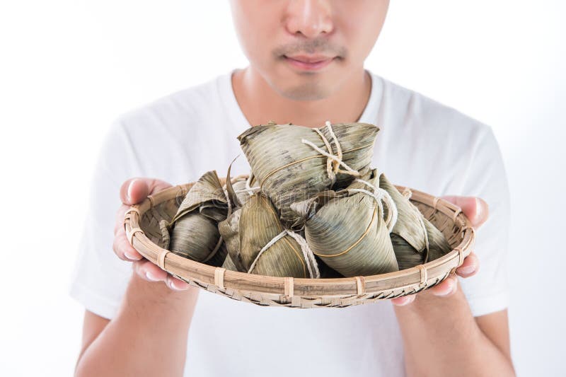 Un uomo dell'Asia sta esaminando Zongzi o lo gnocco del riso con il fronte divertente ed il sorriso e sta ritenendo ha interessat immagine stock libera da diritti Un uomo dell'Asia sta esaminando Zongzi o lo gnocco del riso con il fronte divertente ed il sorriso e sta ritenendo ha interessat immagine stock libera da diritti