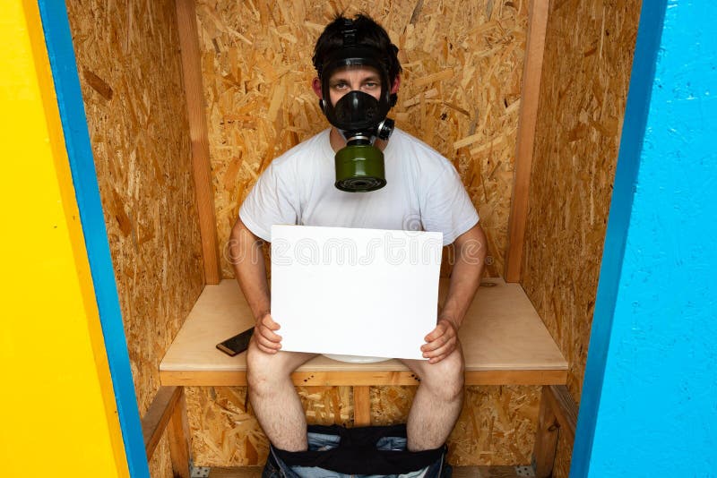 Un uomo mascherato da gas protesta contro un cattivo odore nel bagno fotografia stock Un uomo mascherato da gas protesta contro un cattivo odore nel bagno fotografia stock