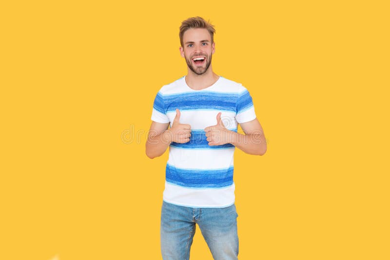 Un uomo millenario che mostra il pollice su isolato sullo sfondo giallo. un uomo millenario indossa un vestito elegante e alla mod