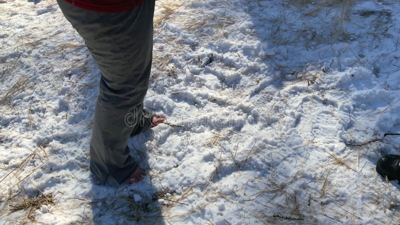 Un uomo sta scalzo nella neve. la ragazza cammina a piedi nudi nella neve.