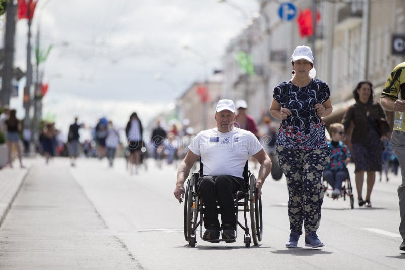 Un uomo su una sedia a rotelle e persone sane competono in una maratona