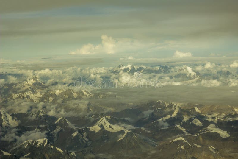 Un valle gris de la montaña del desierto con las montañas y los picos nevosos debajo de las nubes blancas de una gran altura fotos de archivo libres de regalías Un valle gris de la montaña del desierto con las montañas y los picos nevosos debajo de las nubes blancas de una gran altura fotos de archivo libres de regalías