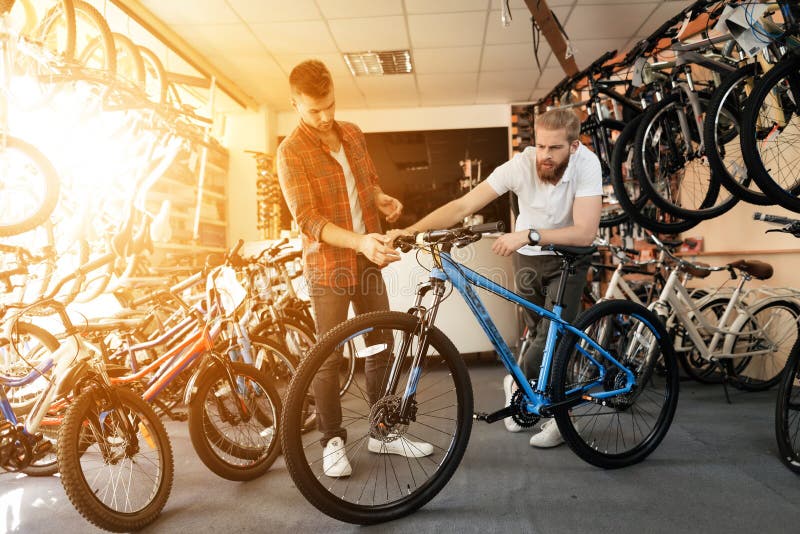 Un vendeur à un magasin de cycles aide un jeune acheteur à choisir un nouveau vélo de montagne photo stock