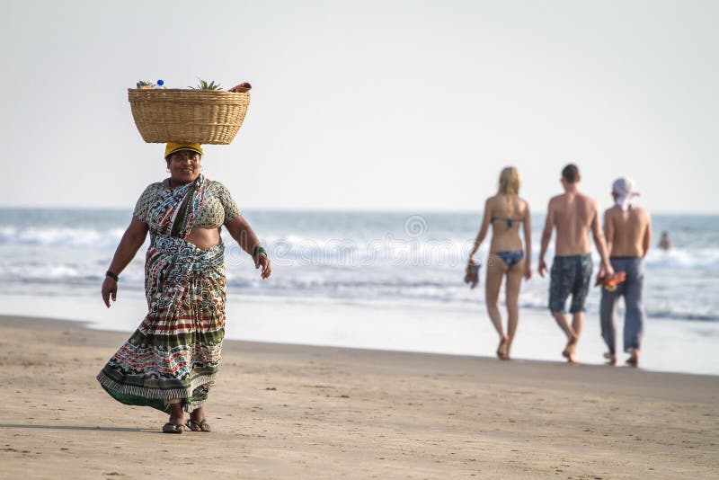 GOA, INDIA - DECEMBER 22, 2012: An unidentified fruit vendor on the beach carrying goods in the basket on her head on December 22, 2012 in Arambol, Goa, India. GOA, INDIA - DECEMBER 22, 2012: An unidentified fruit vendor on the beach carrying goods in the basket on her head on December 22, 2012 in Arambol, Goa, India.