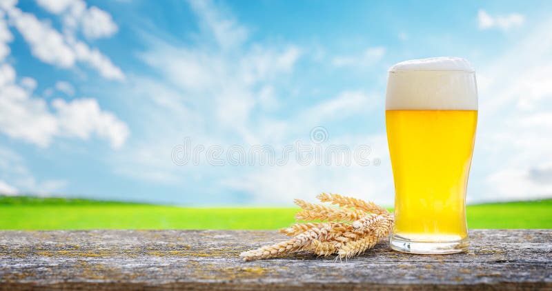 Un verre de bière froide placé sur une table avec un fond de bokeh extérieur doux photographie stock libre de droits