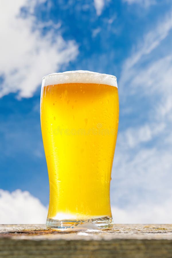 Un verre de bière froide placé sur une table avec un fond de bokeh extérieur doux photos libres de droits