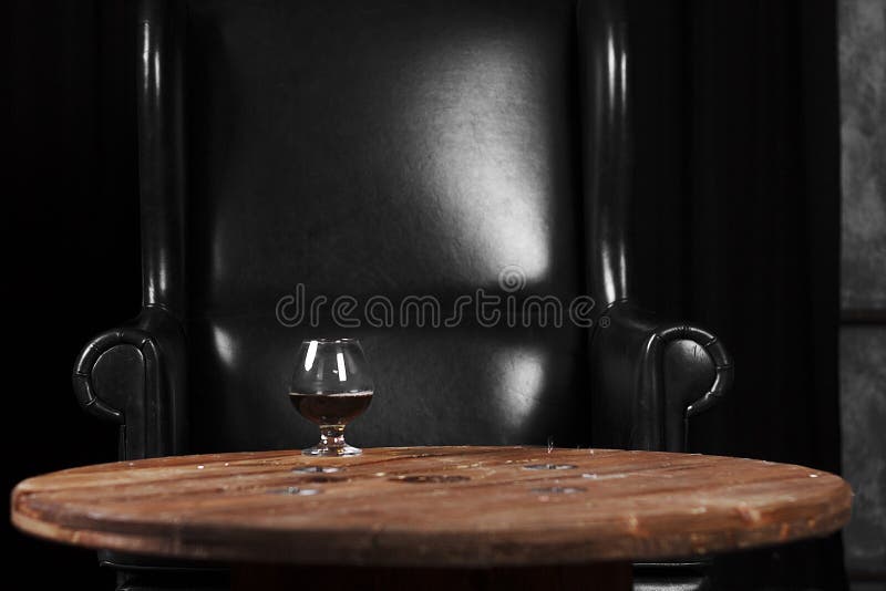 un verre pour le cognac sur une table en bois sur le fond d'une chaise en cuir images stock un verre pour le cognac sur une table en bois sur le fond d'une chaise en cuir images stock