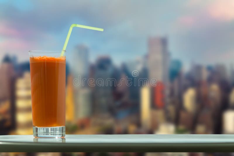 Un vetro del succo di carota con una paglia nel caffè sui precedenti Manhattan New York City immagine stock libera da diritti Un vetro del succo di carota con una paglia nel caffè sui precedenti Manhattan New York City immagine stock libera da diritti